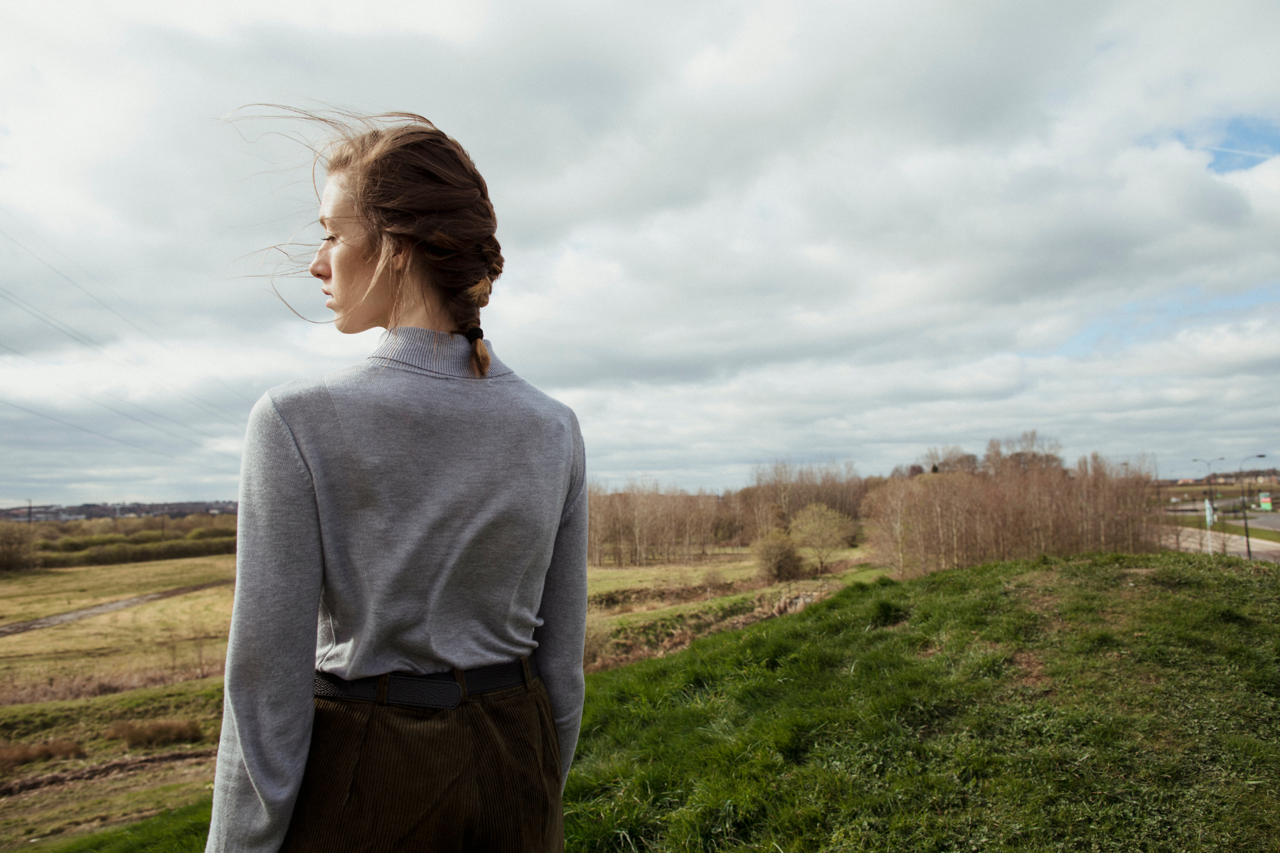 Woman looking out at a landscape as the wind blows her hair.