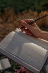 Woman's hand writing in a notebook, positioned outdoors