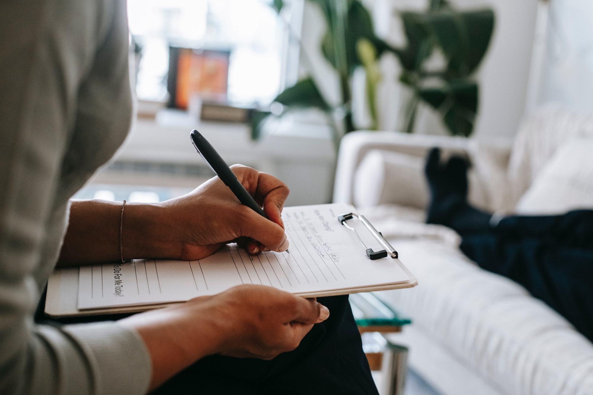 Therapist writing on a clipboard while listening to a patient