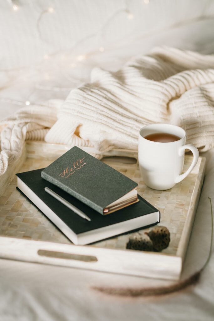 A journal sits on a tray with a cup of coffee representing the self-care practice of journaling learned about in Anxiety Therapy for Women in Manhattan, NY.