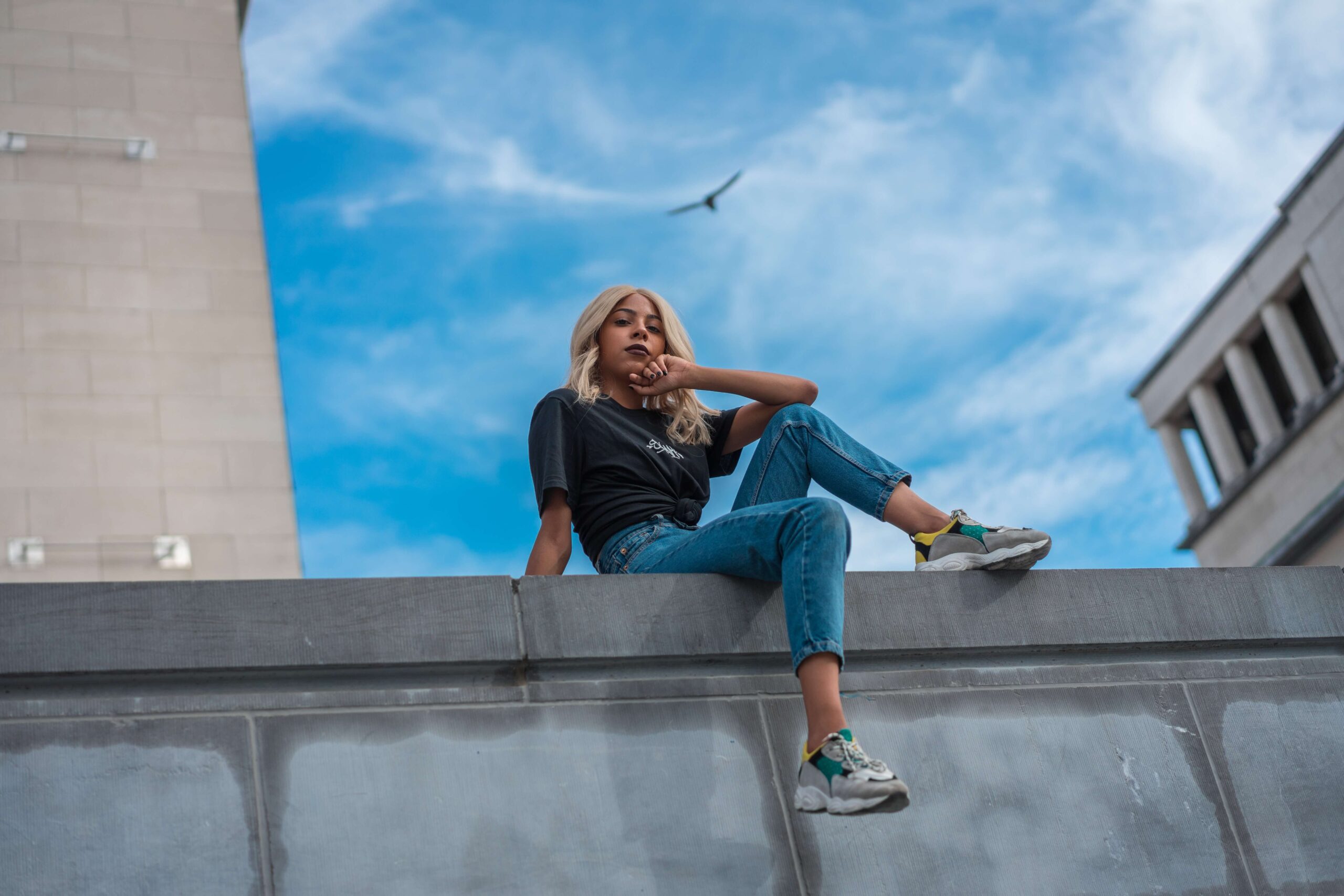 A high-achieving woman sits on a ledge relaxing representing someone who has overcome the feelings of Imposter Syndrome with the help of Therapy for Anxiety in Manhattan, NY.
