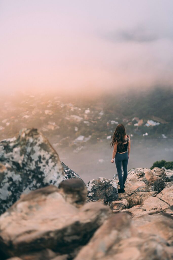 A woman overlooks a valley below as she has climbed to the top of the mountain representing a high-achieving woman who has overcome Imposter Syndrome thanks to Therapy for Anxiety in Manhattan, NY.