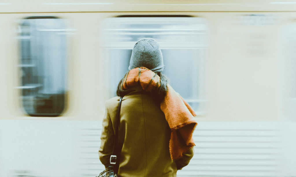 Woman in winter clothing watches as a subway train passes by