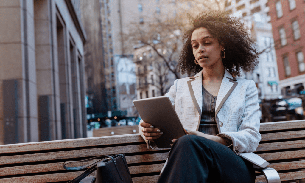 Woman on a park bench reading a tablet
