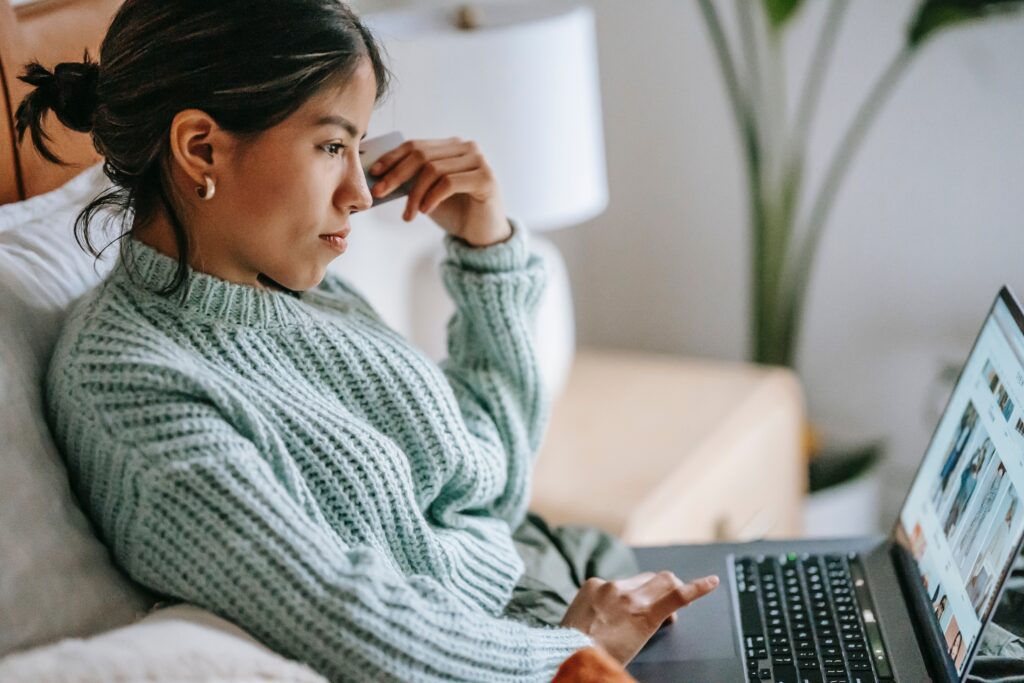 A woman sits looking at her laptop while participating in Therapy for Women in NYC.