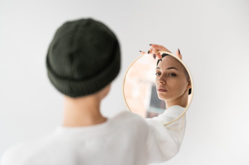 A person looking at themselves. ina mirror that they are holding.