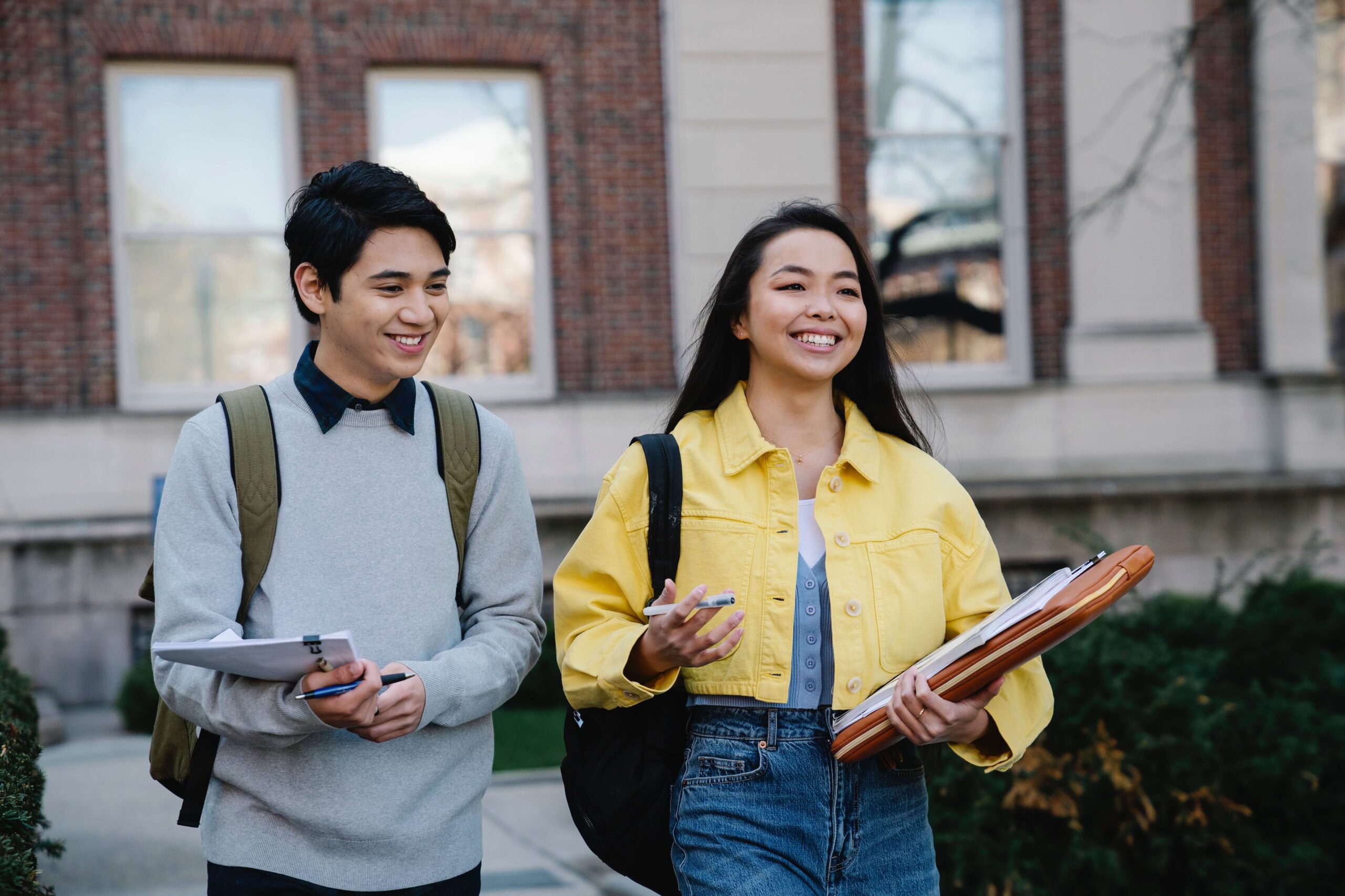 Two high school freshman smile happily as they walk outside the school representing teens who have found support through Therapy for Teens in NYC.