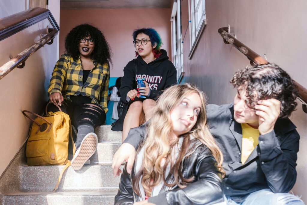 A group of high school seniors sit on the steps as they prepare for the transition to college. Therapy for Teens in NYC can help develop strategies for success.